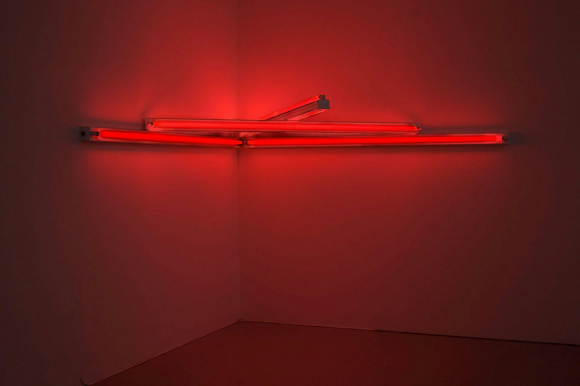 A sculpture in red fluorescent light by Dan Flavin, titled monument 4 for those who have been killed in ambush (to P.K. who reminded me about death), dated 1966.